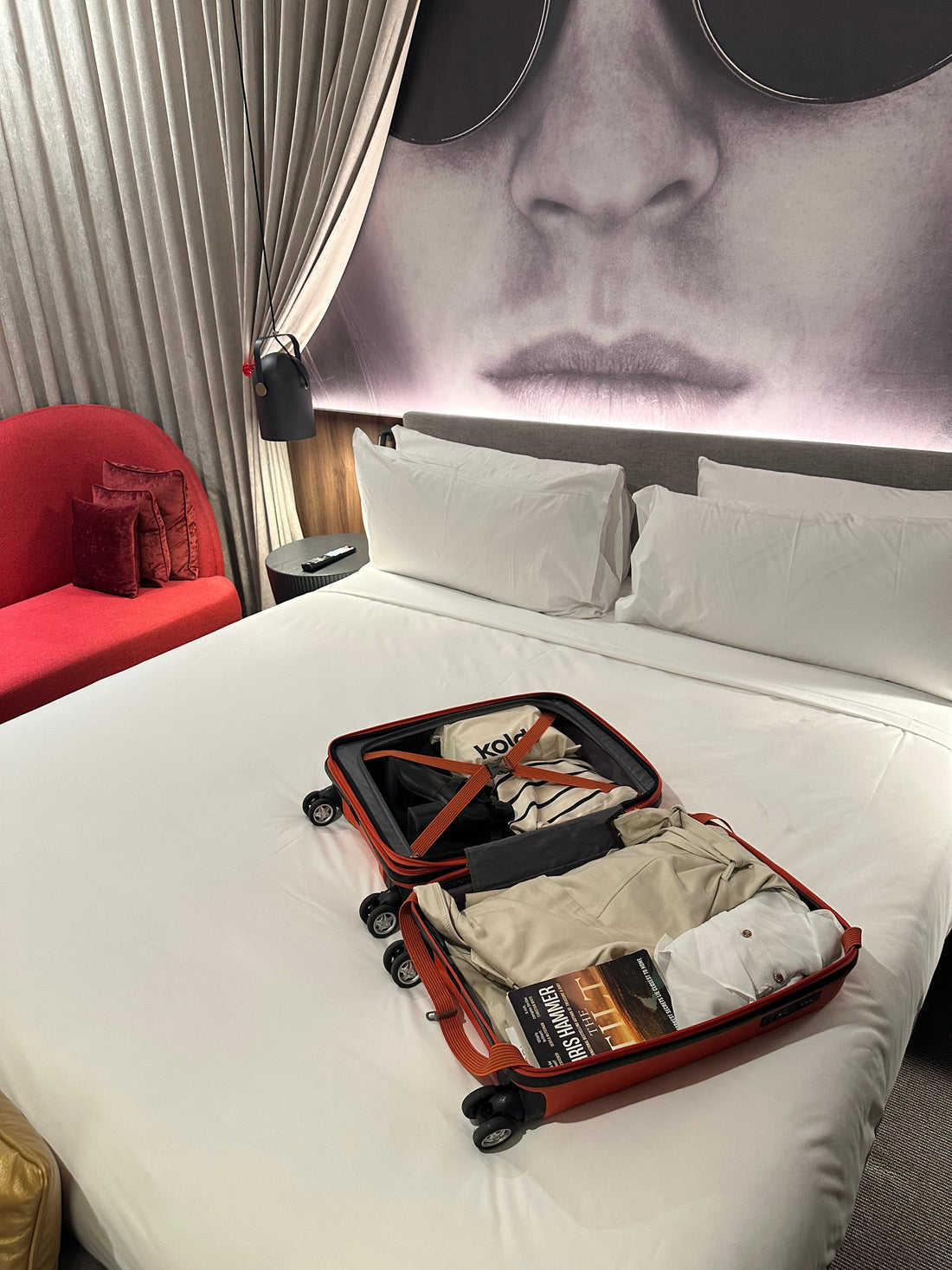 Suitcase open on a hotel bed with makeup bag