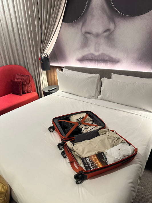 Suitcase open on a hotel bed with makeup bag
