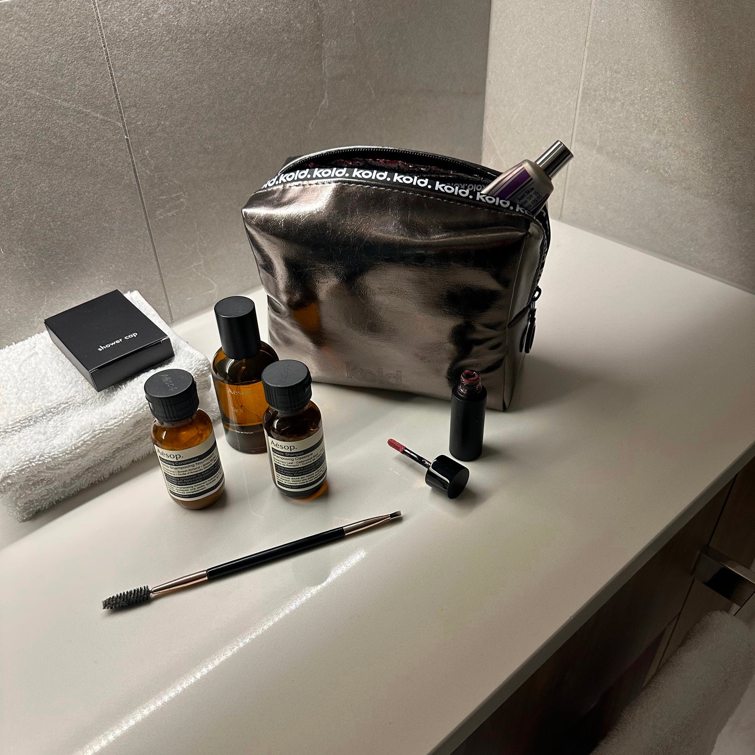 KOLD Chrome beauty bag on bathroom counter next to skincare bottles